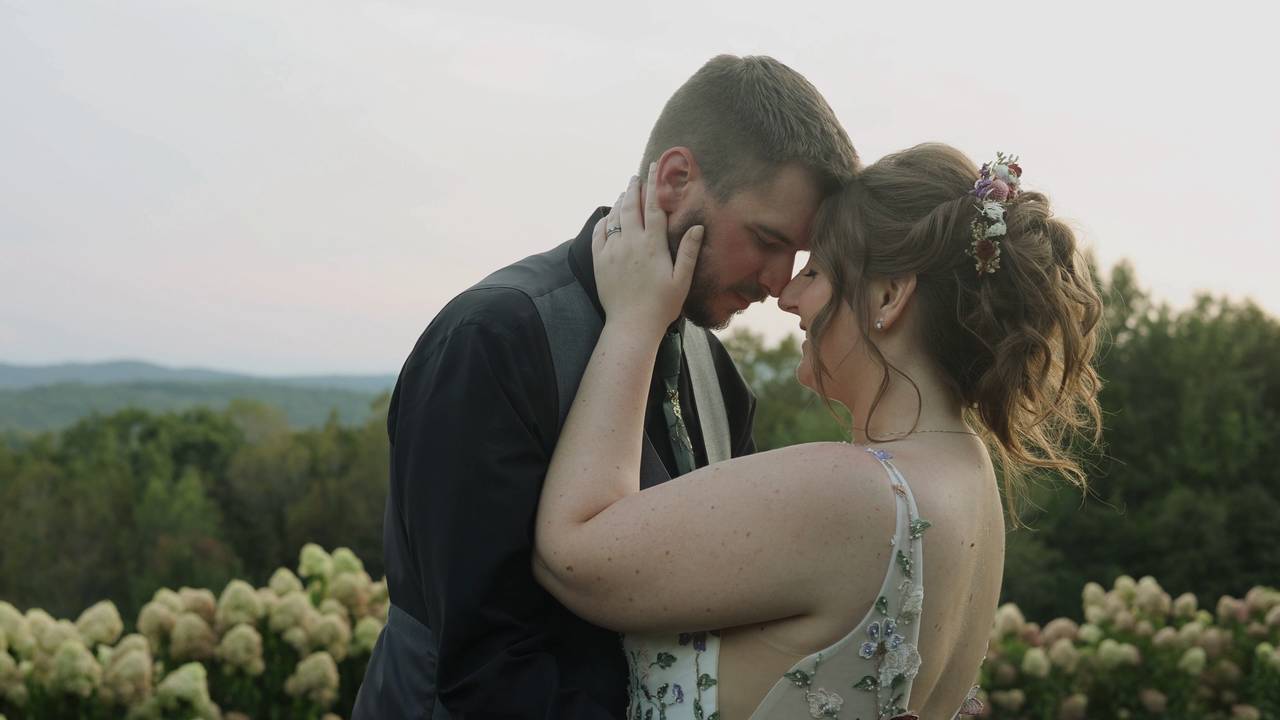 A bride and groom embracing on a hillside at dusk